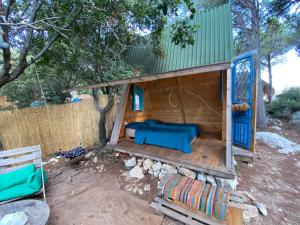 a wooden dog house with a blue bed in it at Snawbar glamping in ‘Ibrīn
