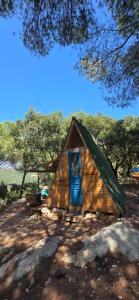 a small wooden house with a blue door at Snawbar glamping in ‘Ibrīn