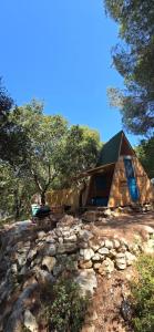 a cabin on a hill with a stone wall at Snawbar glamping in ‘Ibrīn