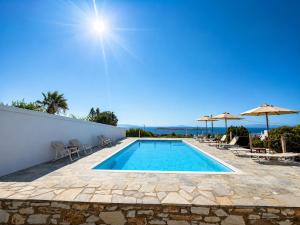 a swimming pool with chairs and umbrellas at Yaleena Residences in Drios