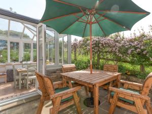 a wooden table with an umbrella on a patio at The Barn - Uk2475 in West Witton