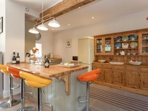 a kitchen with wooden cabinets and orange bar stools at The Barn - Uk2475 in West Witton