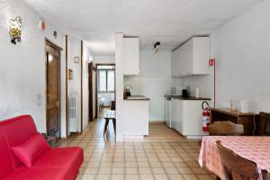 a living room with a red couch and a kitchen at Dolomiti Apartment Pinzolo in Pinzolo