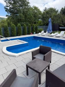 a swimming pool with a table and chairs next to it at Luxury Apartments Sarajevo in Ilijaš