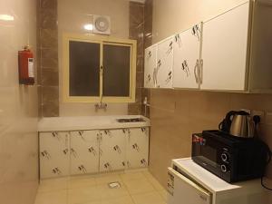 a small kitchen with white cabinets and a microwave at شقق المجد الذهبي للشقق المخدومة in Quai