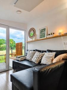 a living room with a black leather couch and a sliding glass door at Chalet Oslo in Bleckede