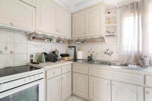 a white kitchen with white cabinets and a sink at A casa d'Irene in Amalias