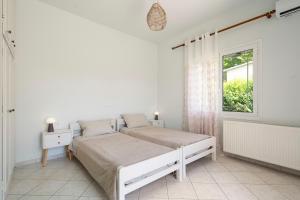 a white bedroom with two beds and a window at A casa d'Irene in Amalias