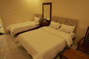 a hotel room with two beds and a mirror at Sri Balakrishna Residency in Thiruchendur