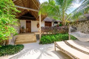 a house with a hammock in front of it at Zanzibar Sunrise at Bandas in Matemwe