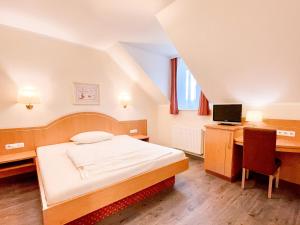 a bedroom with a bed and a desk with a computer at Hotel Kriemhild am Hirschgarten in Munich