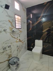 a bathroom with a toilet and a marble wall at Sri Balakrishna Residency in Thiruchendur