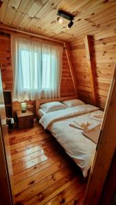 a bed in a wooden room with a window at Riverside Rooms in Šavnik