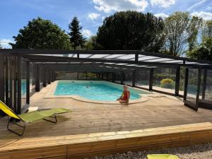 a swimming pool with a pergola and a person sitting on a deck at Domaine du Thie in Dirac