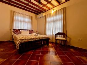 a bedroom with a bed and a chair and a window at Haritham Heritage Villa in Vadakkāncheri