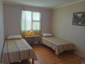 a room with two beds and a desk and a window at Bietjierus Guest Cottage in Twee Riviere