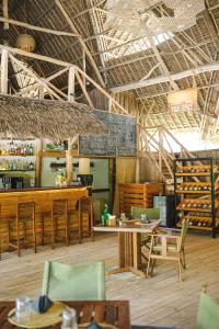 a restaurant with wooden tables and chairs and a bar at Zanzibar Sunrise at Bandas in Matemwe