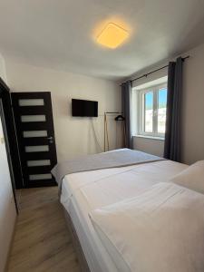 a bedroom with two white beds and a window at Apartmani Brač in Pučišća
