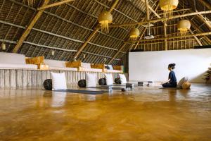 a woman is sitting on a floor in a gym at Zanzibar Sunrise at Bandas in Matemwe +69 photos