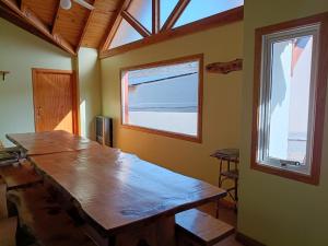 a large wooden table in a room with two windows at Esquel Apart Loft in Esquel