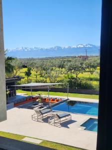 a swimming pool with two chairs and a view of the desert at Atlas villa c3 in Sraghna