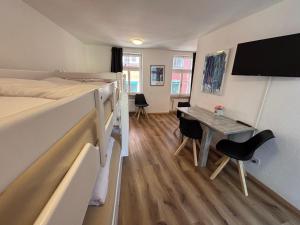 a small room with a bed and a desk with a table at Haus zur Eiche Private 1 Zimmerstudios in Chur