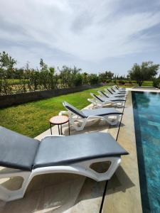 a row of lounge chairs next to a swimming pool at Atlas villa c3 in Sraghna