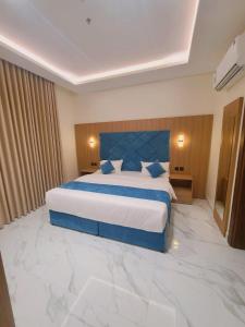 a bedroom with a large bed with a blue headboard at الديار الفاخرة للشقق المخدومة - جيزان in Jazan +4 photos