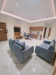 a living room with two blue couches and a kitchen at الديار الفاخرة للشقق المخدومة - جيزان in Jazan