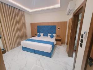 a bedroom with a large bed with a blue headboard at الديار الفاخرة للشقق المخدومة - جيزان in Jazan