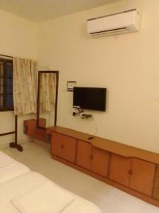 a living room with a tv at Coral Shelters Service Apartments Thuvariman in Madurai