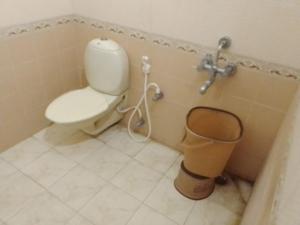 a bathroom with a toilet and a trash can at Coral Shelters Service Apartments Thuvariman in Madurai