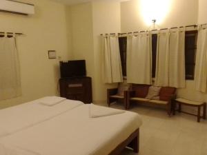 a bedroom with two beds and a television in it at Coral Shelters Service Apartments Thuvariman in Madurai