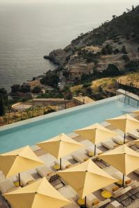a pool with yellow umbrellas next to the water at Gran Hotel Margalida by Annua Signature in Banyalbufar