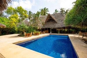 a swimming pool in front of a villa at Zanzibar Sunrise at Bandas in Matemwe