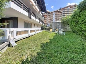 a yard of a building with tables and chairs at Apartment Hauts De Nendaz B OP by Interhome in Nendaz