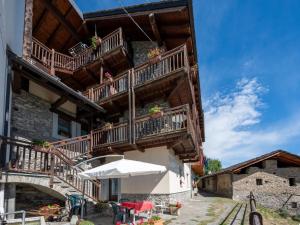 a building with wooden balconies and tables and an umbrella at Apartment Grand Sarriod-5 by Interhome in Saint Nicolas