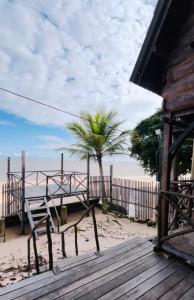 a bench on the beach with a palm tree at CHALÉ SERINGUEIRA in Outeiro