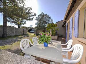 a table with white chairs and a potted plant on it at Holiday Home Le Real by Interhome in Velleron