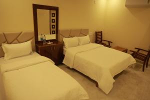 a hotel room with two beds and a mirror at Sri Balakrishna Residency in Thiruchendur +6 photos