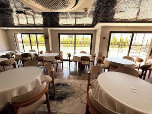a room with white tables and chairs and windows at Ovva Inn Yeşilovacık Hotel in Dibekli