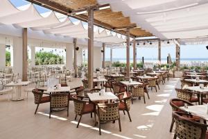 a restaurant with tables and chairs with the ocean in the background at Adalya Ocean Deluxe - Ultra All Inclusive in Side