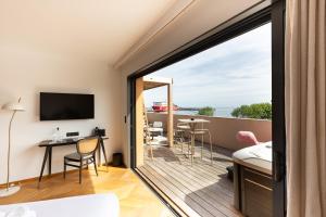 a room with a balcony with a view of the ocean at Hôtel & Spa Rocabella in LʼÎle-Rousse