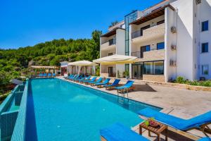 a swimming pool with blue lounge chairs next to a building at Turquoise Retreat Spa & Wellness in Kaş