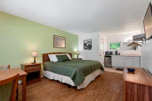a bedroom with a green bed and a kitchen at Trailhead Lodge in Eureka Springs