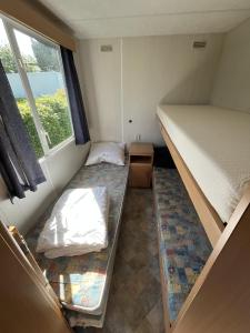 ein kleines Zimmer mit zwei Betten und einem Fenster in der Unterkunft Camping BuitenRijk - Chalet D36 Huisdiervriendelijk in Valthermond