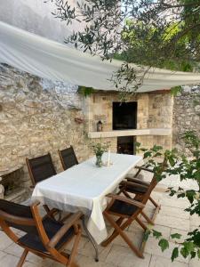 a table and chairs with a white table and a tv at Apartmani Brač in Pučišća