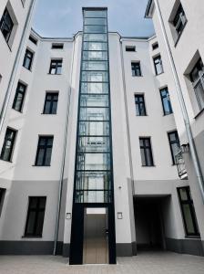 a tall white building with a glass elevator at WSCHODNIA ELEGANS Aparthotel in Łódź
