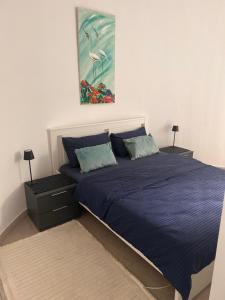 a bedroom with a blue bed with a painting on the wall at Apartman 4N with free parking in Belgrade