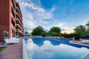 ein Schwimmbad mit Liegestühlen neben einem Gebäude in der Unterkunft Gladiola 3-star in Goldstrand + 7 Fotos